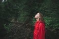 Portrait of a young woman traveler enjoying trip to the mountain forest with her eyes closed. Tourist girl in red jacket raising Royalty Free Stock Photo