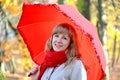 Portrait of the young woman under a red umbrella in the autumn park Royalty Free Stock Photo