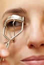 Portrait of young woman using an eyelash curler Royalty Free Stock Photo