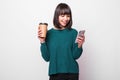 Portrait of young woman using mobile phone while holding cup of coffee to go isolated over white background Royalty Free Stock Photo