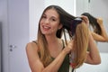 Portrait of young woman using round brush hair dryer to style hair in an easy way at home. Girl with electric blowout brush hair Royalty Free Stock Photo