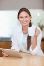 Portrait of a young woman using a tablet computer while drinking Royalty Free Stock Photo