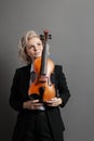 Portrait of an young woman violinist in a black male suit with a violin looking up Royalty Free Stock Photo