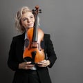 Portrait of an young woman violinist in a black male suit with a violin looking up Royalty Free Stock Photo