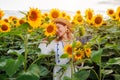 Portrait of young woman walking in blooming sunflower field at sunset smelling picking flowers. Summer in Ukraine Royalty Free Stock Photo