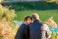 Portrait of young woman watching in camera with near sitting her lover. Couple hugging and relaxing near forest lake. Love Royalty Free Stock Photo