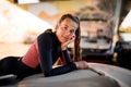 Portrait of young woman wearing a black wetsuit lies with her head propped with her hand Royalty Free Stock Photo