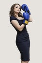 Portrait of a young woman wearing blue boxing gloves against gray background