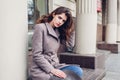 Portrait of young woman wearing grey coat outdoors holding hat. Spring fashion female retro accessories outfit Royalty Free Stock Photo