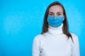 Portrait of young woman wearing medical mask at blue background. Protect your health. Coronavirus concept Royalty Free Stock Photo