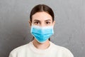 Portrait of young woman wearing medical mask at gray cement background. Protect your health. Coronavirus concept Royalty Free Stock Photo