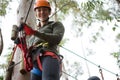 Young woman wearing safety helmet holding zip line cable in the forest