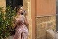 Portrait of young woman wearing summer pink striped dress, sitting near olive tree, drinking coffee, enjoying aroma. Royalty Free Stock Photo