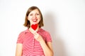 Portrait of the young woman on a white background with a red heart lollipop in her hand. Royalty Free Stock Photo