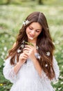 Portrait of a young woman in a white dress with primroses. A girl in the spring forest. White anemones in long brown hair Royalty Free Stock Photo