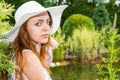 Portrait of a young woman in white hat sitting near the lake Royalty Free Stock Photo
