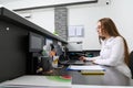 Portrait of woman administrator at reception desk, making appointments with the medical staff while sitting at laptop pc