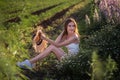 Portrait of a young woman who laughs with an open smile, holding a straw hat, holding wild daisies. A girl sits among a field of Royalty Free Stock Photo