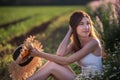 Portrait of a young woman who laughs with an open smile, holding a straw hat, holding wild daisies. A girl sits among a field of Royalty Free Stock Photo