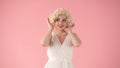 Portrait young woman in wig, white dress and with red lipstick on lips in studio on pink background. Woman looking like Royalty Free Stock Photo