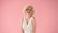 Portrait young woman in wig, white dress and with red lipstick on lips in studio on pink background. Woman looking like Royalty Free Stock Photo