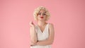 Portrait young woman in wig, white dress and with red lipstick on lips in studio on pink background. Woman looking like Royalty Free Stock Photo