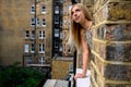 Portrait of young woman wistfully looking out of the window of an old brick building and hoping for better things to come in Royalty Free Stock Photo