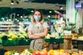 Portrait young woman worker seller in a Vegetable section supermarket standing in a protected face mask arms crossed. greengrocer Royalty Free Stock Photo