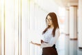 Portrait of young business woman working holding laptop standing against panoramic window with city view Royalty Free Stock Photo