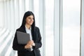 Portrait of young woman working holding laptop standing against panoramic window with city view Royalty Free Stock Photo