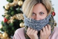 Portrait of young woman wrapped in scarf on background of Christmas tree Royalty Free Stock Photo