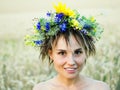 Portrait of a young woman in a wreath of wild flowers stands in the field at sunset. Royalty Free Stock Photo