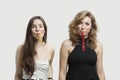 Portrait of young women blowing party puffers against gray background