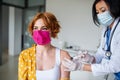 Young woman with face mask getting vaccinated in hospital, coronavirus and vaccination concept.