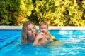 Portrait of young woman instructor swimming in the pool with her little girl Royalty Free Stock Photo