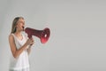 Portrait of young women shouting using megaphone over background Girl in white shirt, studio shot . Royalty Free Stock Photo