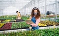 Young woman working in greenhouse in garden center, coronavirus concept.