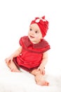 Portrait of young 1 year old baby girl in red dress with red hat on her head looking away