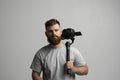 Portraite of bearded cinematographer in a grey t-shitr with a camera and 3-axes gimbal on a white background