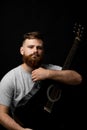 Portraite of bearded handsome musician holding a guitar in a dark room. Guitarist, artist, composer, rocker, star.