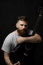 Portraite of handsome brunette bearded man musician, guitarist holding a acoustic guitar in a hand and looks in a camera