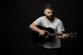 Portraite of handsome brunette bearded man musician, guitarist standing and holding a acoustic guitar in a hand.