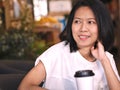 Portraits of Asian woman looking to her right hand with smile face in cozy coffee shop. Royalty Free Stock Photo