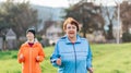 Portraits of the grandmother and granddaughter running together. Mature and young women in sports clothes, jogging in