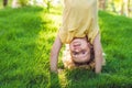 Portraits of happy kids playing upside down outdoors in summer park walking on hands