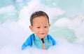 Portraits of happy little Asian baby boy smiling having fun in Foam Party at the pool outdoor