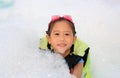 Portraits of happy little Asian child girl smiling having fun in Foam Party at the pool outdoor