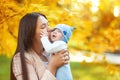 portraits of mom and baby in autumn park, mom hugs and kisses baby