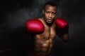 Portratit of african american boxer punching with red glove in darg background, selective focused