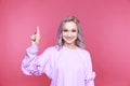 Portraut of happy girl showing up and pointing something on the pink background.